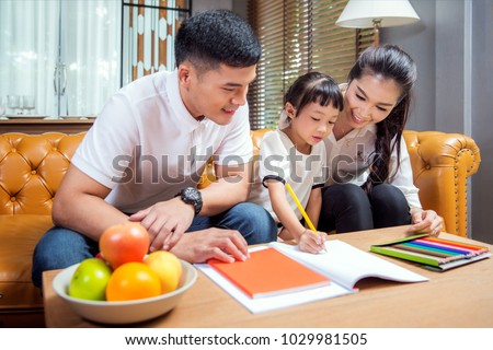 Asian father, mother and daughter doing home work togather in living room, this immage can use for education, home and family concept