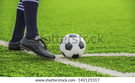 soccer ball with his feet on the football field