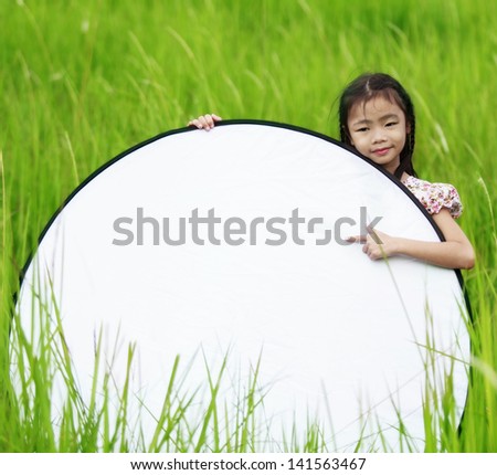 Cute little girl on neutral background holding sign used for your text