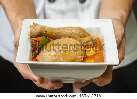 chicken mussaman curry with cook or chef hand between served
