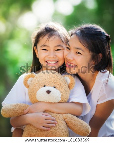 Asia little girl and her mather with doll bear in nature park