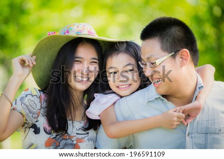 Happy asian mother, father and daughter playing in the park