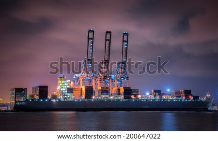Container Cargo freight ship with working crane loading bridge in shipyard at dusk for Logistic Import Export background
