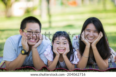 Happy asian mother, father and daughter relax in the park