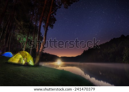 Small Camping Tent Illuminated Inside. Night Hours Campsite. Recreation and Outdoor Photo Collection.
