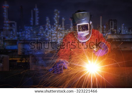 worker with protective mask welding metal and sparks in oil refinary plant.