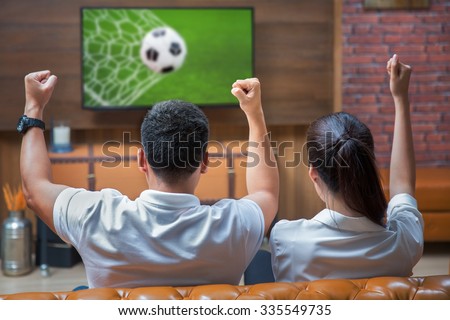 Asian Couple having fun watching soccer game
