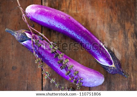 Photo of two Japanese  eggplants with water droplets on a wood table