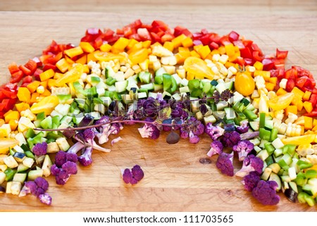 Cut vegetables arranged as a rainbow on wooden surface.Also available in vertical format.