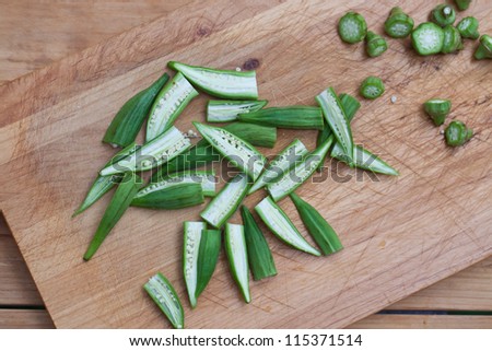 Cut okra on a cutting board . Also available in vertical format.
