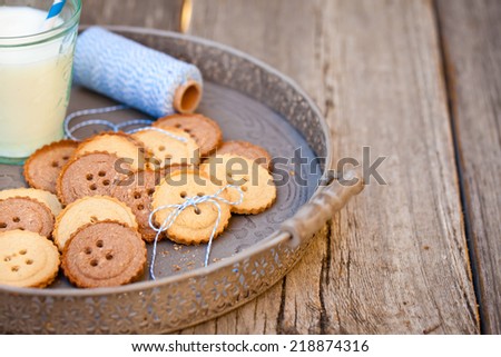 Sugar cookies in shape of buttons on wooden table with a glass of milk. Also available in vertical format. Copy space.