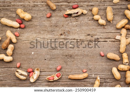 Frame from peanuts in shells on wood background. Copy space.