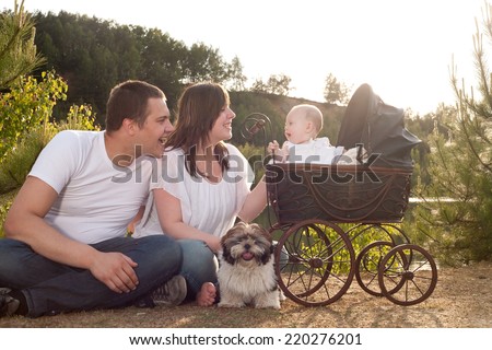 Portrait of parents with their baby girl is sitting in a vintage pram