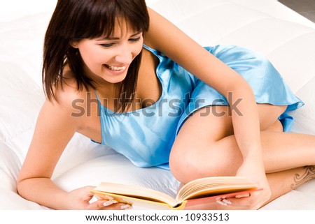 Brunette in pyjama\'s reading a book in bed. Titles have been made unreadable so no copyright infrigment.
