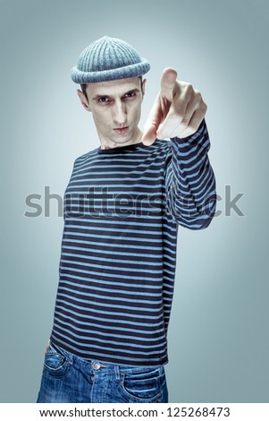 Portrait of goofy guy in knitted hat. Pointing finger,