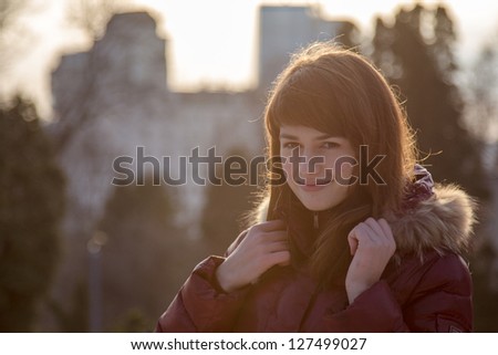 Portrait of the beautiful young woman in winter city park.