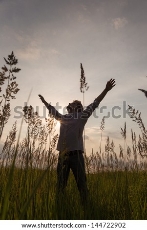 Expressive happy man with hands up on sunset background.