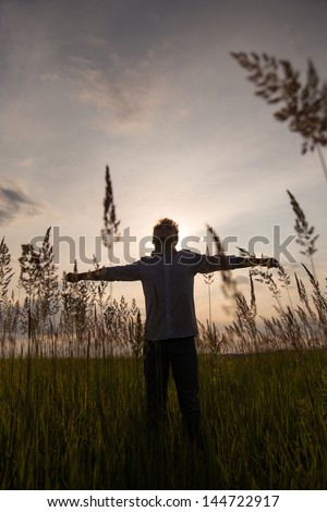 Expressive happy man with hands up on sunset background.