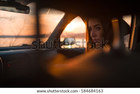 Portrait of beautiful young woman in hat, on the passenger seat in the car.