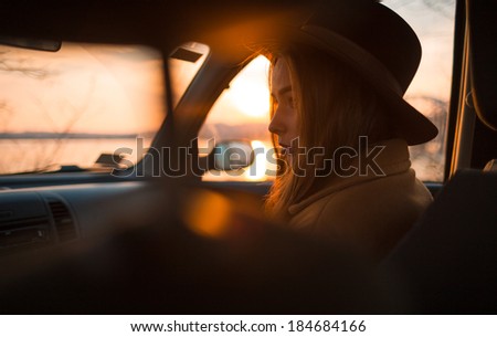 Portrait of beautiful young woman in hat, on the passenger seat in the car.