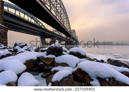 Snow on the river stones at the bank of the Dnieper river in Kiev. Near the Darnitsky bridge.