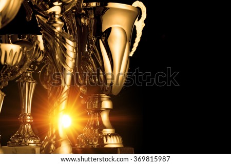 Group of the golden trophies in sparkling light on the dark background.