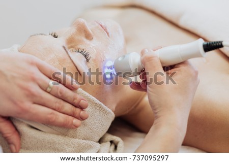 Woman getting laser and ultrasound face treatment in medical spa center