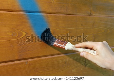the hand with the brush draws a blue line on a wooden wall, Russia, near Moscow