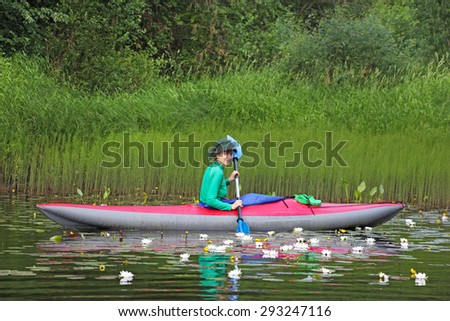 girl on kayak among water lilies(nymphaea, nuphar), river Vetluga, Russia