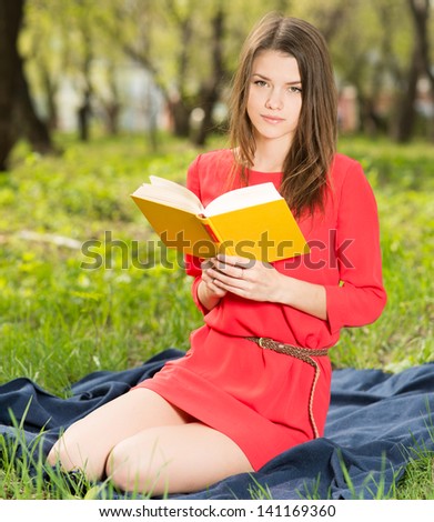 beautiful young girl reads book in park