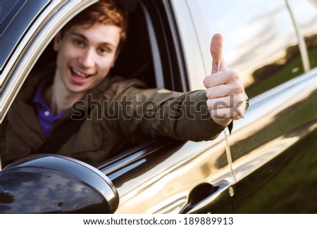 Happy man in his new car shows thumb up