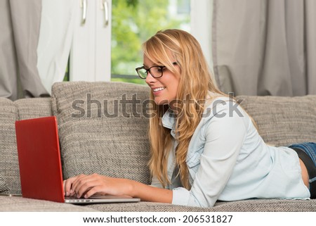 pretty woman with a laptop laying at couch