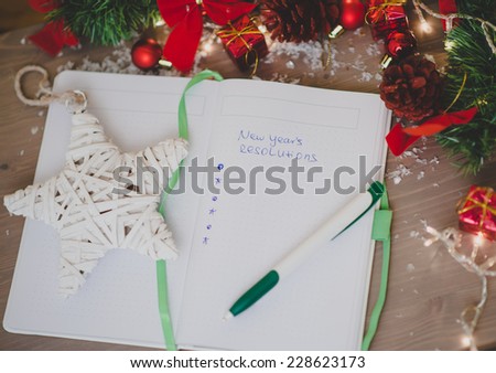New year\'s resolutions written on a notepad with a star and new years decorations
