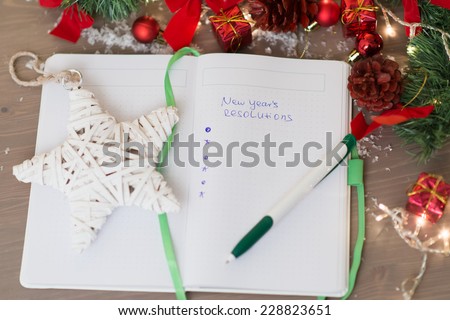 New year\'s resolutions written on a notepad with a star and new years decorations