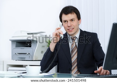 business man in office speaks on telephone