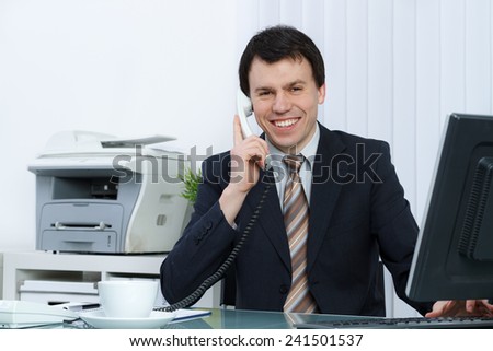 business man in office speaks on telephone