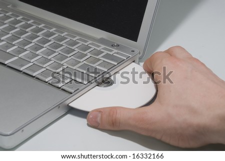 Hand inserting DVD into laptop