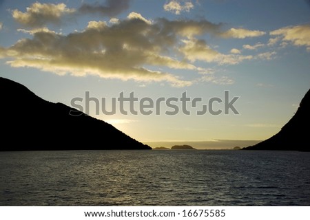 Sun setting over horizon with silloughetted hills in foreground