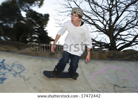 Skate boarder moving along rim of bowl
