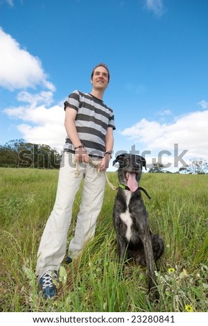 Male standing in grassy field with pet dog