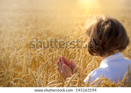 Woman holds wheat and pray for harvest