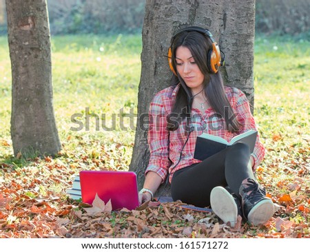 Beautiful autumn day, a young girl - student learns outdoors