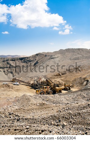 Wheel front-end loader unloading ore into bunker  which is transported by conveyor belt to to Processing Plant