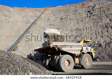 Wheel front-end loader unloading  ore into heavy dump truck at the opencast mining