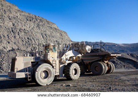 Wheel front-end loader unloading ore into heavy dump truck at the opencast mining