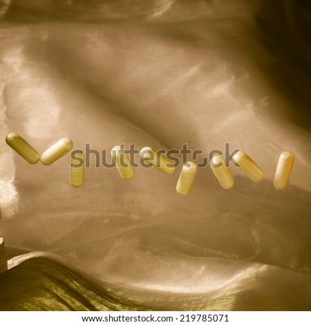 Levitating Pharmaceutical Capsules /Pills Floating on Shimmering Gold Background
