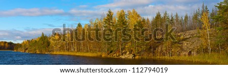 Rocky coast of the wood lake in the autumn