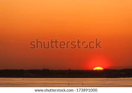 the sun sets over the horizon over the sea shore