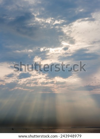evening skyscape above the sea with the sun behind the clouds