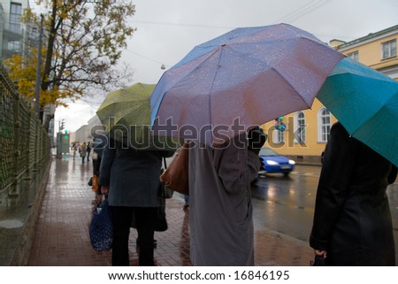 People with umbrellas expect public transport in rainy day